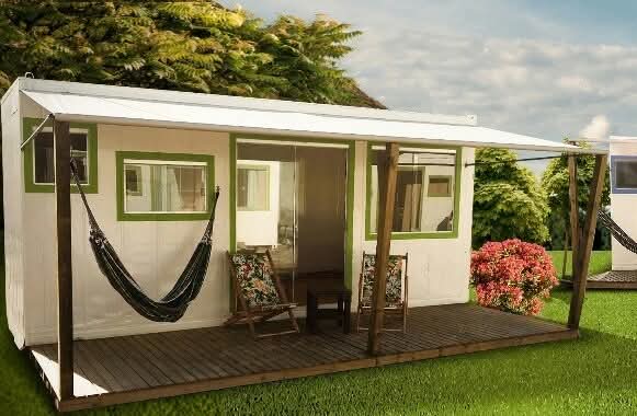 Mini casa branca com molduras verdes, varanda e rede